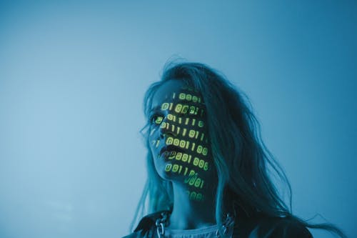 Free A woman with binary code lights projected on her face, symbolizing technology. Stock Photo